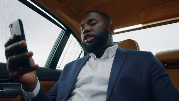 Primer plano hombre africano teniendo videollamada en el coche. Hombre de negocios hablando de teléfono en el coche
 - Foto, imagen