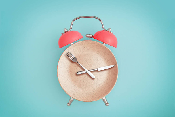 Alarm clock and plate with cutlery . Concept of intermittent fasting, lunchtime, diet and weight loss - Photo, Image
