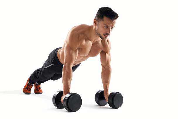 Muscular man doing push ups using dumbbells. - Fotoğraf, Görsel