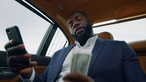 Blízký africký muž, který dělá videohovory v autě. Afro muž třese penězi na zadním sedadle - Fotografie, Obrázek