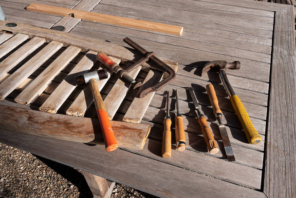 Las herramientas de un carpintero yacen en una mesa de madera afuera al sol
 - Foto, Imagen