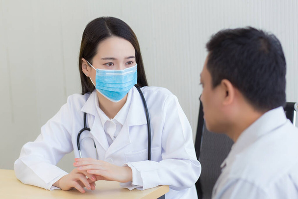 Coronavirus védelmi koncepció.Ázsiai női orvos kérdéseket tesz fel a betegeknek azzal, hogy mindig sebészeti maszkot visel. - Fotó, kép