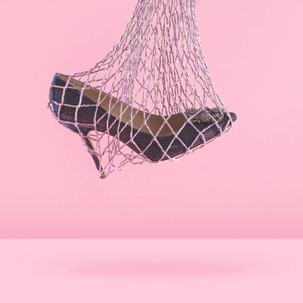 Luksusowy błyszczący but na wysokim obcasie wiszący w pięknej siatkowej torbie na różowym tle, reklama butów, baner, makieta - Zdjęcie, obraz