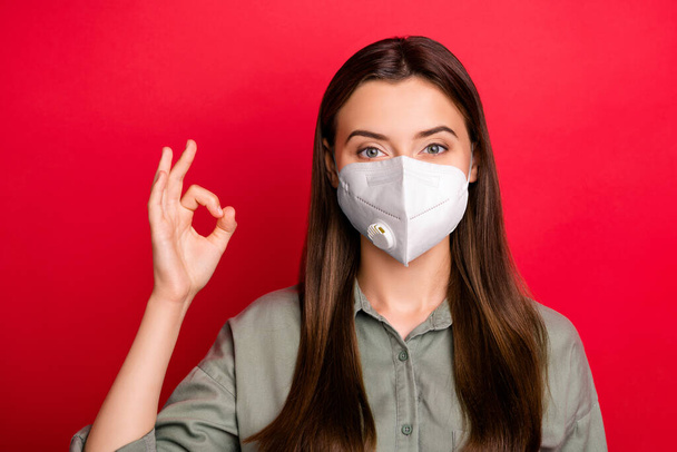 Close-up portrait of her she nice attractive straight-haired girl wearing n95 safety respirator mask showing ok-sign mers cov prevention isolated over bright vivid shine vibrant red color background - Photo, Image