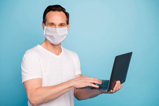 Portrait of his he nice skilled guy wearing safety mask working remotely on laptop watch video lesson stop flu grippe disease case healthcare isolated bright vivid shine vibrant blue color background - Foto, imagen