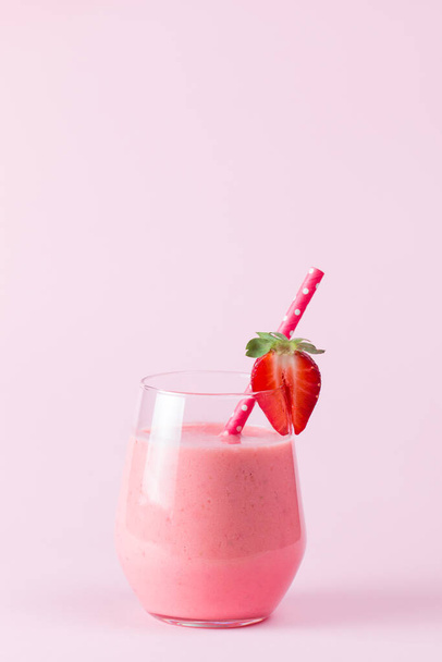 A glass of fresh strawberry smoothie on a wooden background. Summer drink shake, milkshake, juice and refreshment organic concept. - Foto, imagen