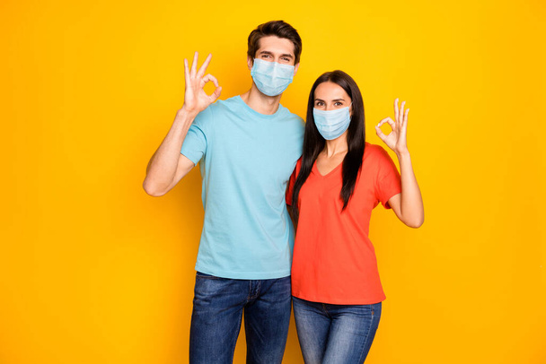 Portrait of his he her she lovely healthy couple guy lady embracing showing ok-sign wearing gauze safety mask stop mers cov infection flu influenza contamination isolated over yellow color background - Фото, зображення