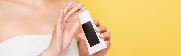 cropped view of woman holding hand cream isolated on yellow, panoramic shot - 写真・画像