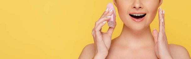 cropped view of shocked beautiful naked woman holding facial cleansing brush isolated on yellow, panoramic shot - Фото, зображення
