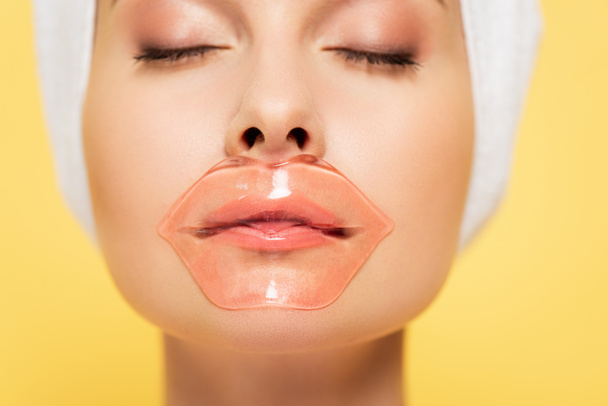 close up view of beautiful woman with lip patch and closed eyes isolated on yellow - Photo, Image