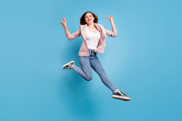 Full body photo of cheerful lovely pretty girl jump make v-sign wear plaid blazer sneakers isolated over blue color background - Foto, imagen