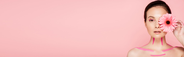 hermosa mujer desnuda con líneas de color rosa en el cuerpo y crisantemo cerca de ojo aislado en rosa, tiro panorámico
 - Foto, Imagen