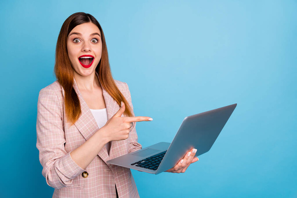 Portrait of excited shocked girl manager work home laptop point index finger screen impressed social media promotion wear plaid jacket isolated over blue color background - Photo, image