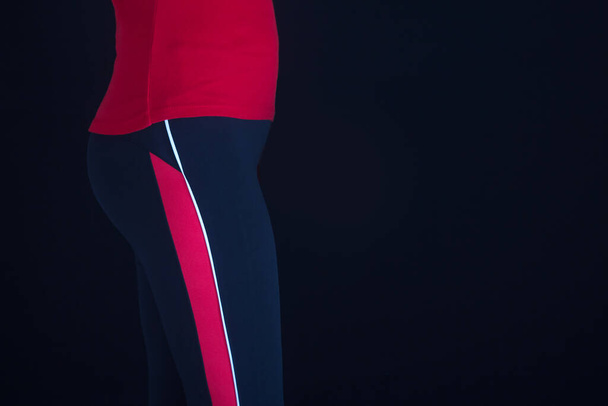 Fashion Sportswear. Fit Long Woman Legs In Leggings. Legs of a sexy girl in black and red leggings. Mock-up. Wearing sports clothing. Recovery figures after pregnancy. Weight loss, healthy lifestyle - Foto, imagen