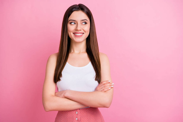Photo of cute attractive lady good mood beaming smile long perfect hairdo look side empty space arms crossed wear casual white singlet isolated pastel pink color background - 写真・画像