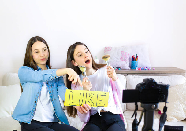 Two beauty blogger cute girls presenting beauty cosmetic products and broadcasting live video to social network. Focus on the blogger teen girls influencer. Beauty blogger and vlog concept for teenager followers. - Fotoğraf, Görsel
