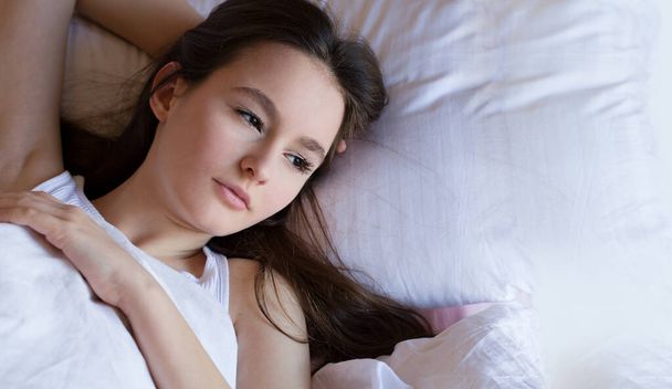 Durmiendo chica adolescente disfrutando de una siesta saludable en la cama acogedora por la mañana, chica milenaria relajándose en una almohada suave y cómodo colchón con algodón blanco
. - Foto, imagen