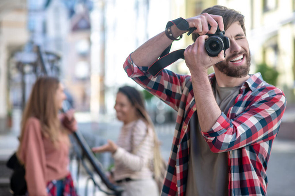 Guy in plaid shirt photographing on camera on street. - Foto, afbeelding