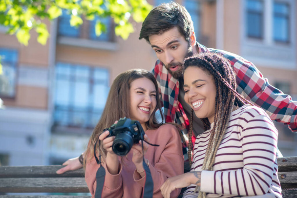 Having fun grimacing guy and two girls with camera - Foto, imagen