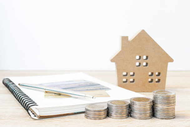 Ház modell és jegyzettömb érmékkel az asztalon a pénzügyi és banki koncepció - Fotó, kép
