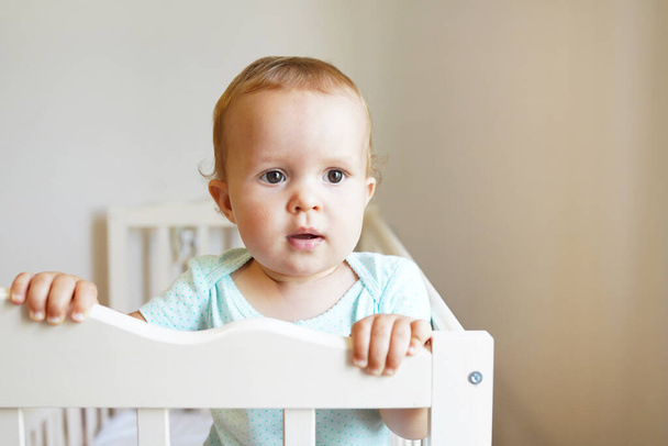 Little child standing in baby crib, lovely kid looking out the little bed - Photo, Image