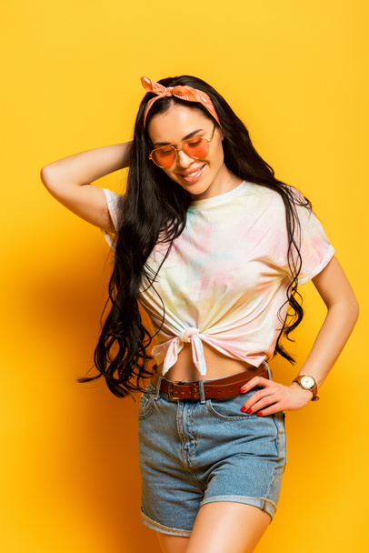 smiling stylish summer brunette girl with hand on hip on yellow background - Foto, Imagem
