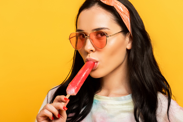 stylish summer brunette girl eating ice cream isolated on yellow - Fotografie, Obrázek
