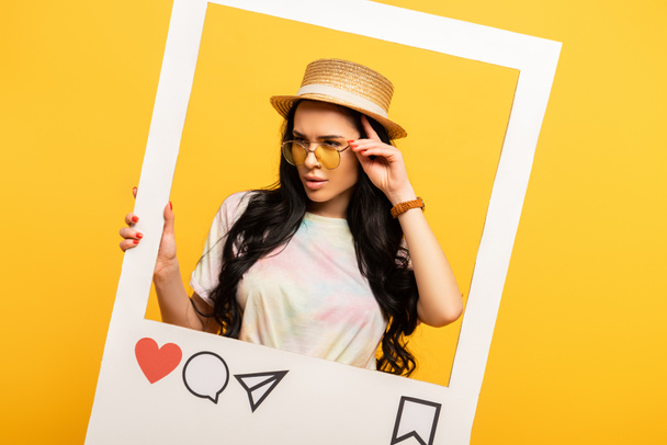 serieus brunette meisje in de zomer outfit poseren in sociaal netwerk frame op gele achtergrond - Foto, afbeelding