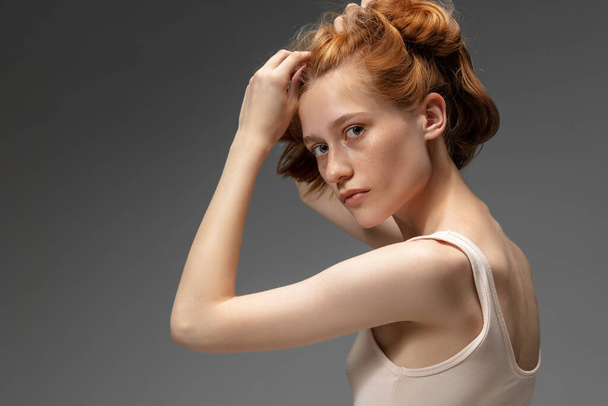 Portrait of beautiful redhead woman isolated on grey studio background. Concept of beauty, skin care, fashion and style - Photo, image