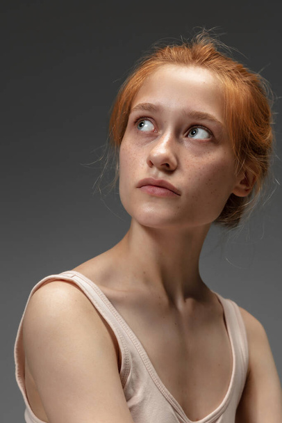 Portrait of beautiful redhead woman isolated on grey studio background. Concept of beauty, skin care, fashion and style - 写真・画像