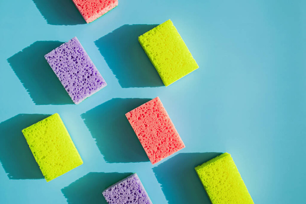 Cleaning sponges for washing dishes on blue background in natural light with hard shadows. Cleaning service concept - Foto, imagen