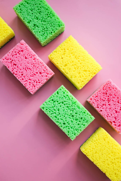 Cleaning sponges for washing dishes on pink background in natural light with hard shadows. Cleaning service concept - Fotó, kép
