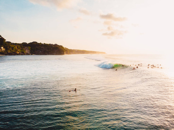 Dalgalar, sörfçüler ve günbatımı ışıklarıyla okyanus manzarası. Bali 'de Drone görünümü - Fotoğraf, Görsel