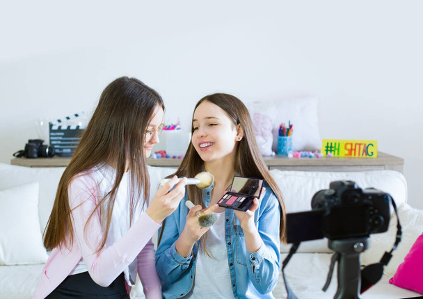 Δύο έφηβες blogger παρουσιάζουν προϊόντα ομορφιάς και μεταδίδουν ζωντανά βίντεο στα κοινωνικά δίκτυα. Συγκεντρώσου στην επιρροή των εφήβων blogger κοριτσιών. Beauty blogger και έννοια vlog. - Φωτογραφία, εικόνα
