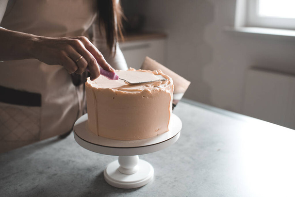 Woman making creamy birthday cake in kitchen closeup. Holiday time. Selective focus.  - Photo, Image