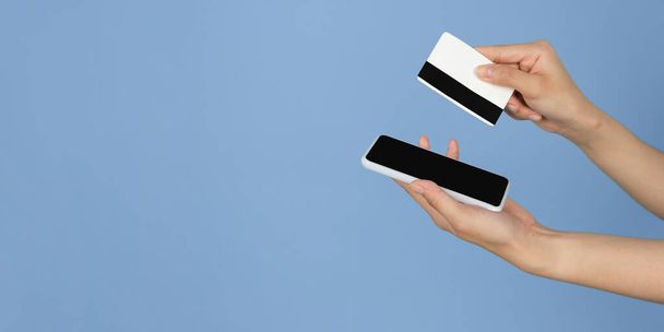 Female hands with phone, credit card and tablet with copyspace on blank screen - Фото, изображение
