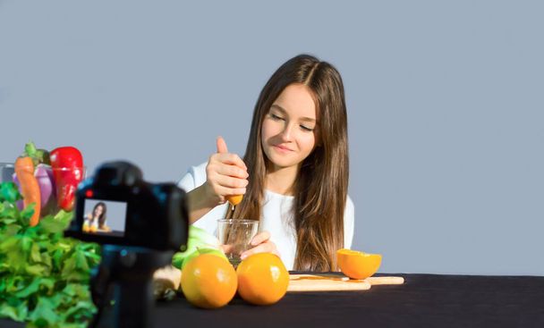 10代のブロガーは、有機果物や野菜を食べるという利点についてフォロワーに話します。健康的なライフスタイルと健康的な食べ物のために幸福への利点の若い影響力者による青年へのコミュニケーションの概念 - 写真・画像