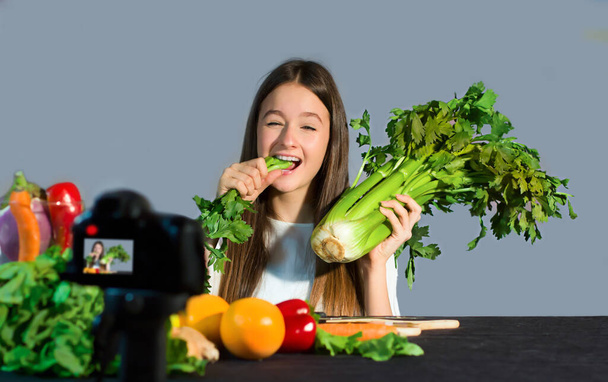 O blogueiro adolescente fala com os seguidores sobre as vantagens de comer frutas e vegetais orgânicos. Conceito de comunicação aos adolescentes por um jovem influenciador dos benefícios sobre o bem-estar devido ao estilo de vida saudável e alimentação saudável
 - Foto, Imagem