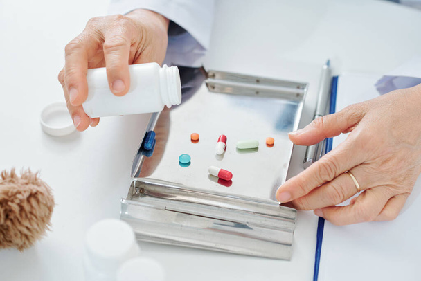 Médico general poniendo pastillas y tabletas en bandeja de acero inoxidable para facilitar la clasificación y el conteo - Foto, imagen