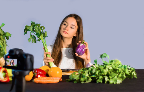 Teini-ikäinen bloggaaja puhuu seuraajille orgaanisten hedelmien ja vihannesten syömisen eduista. Nuoren vaikuttajan käsitys terveellisestä elämäntavasta ja terveellisestä ruoasta johtuvasta hyvinvoinnista - Valokuva, kuva