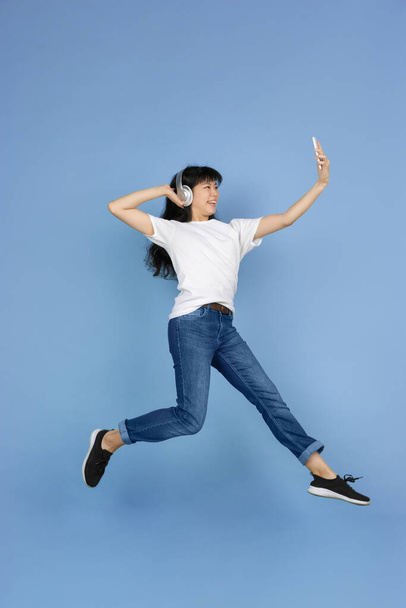Porträt einer jungen asiatischen Frau isoliert auf blauem Studiohintergrund - Foto, Bild