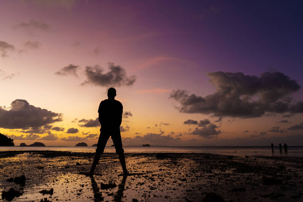 Miehen siluetti rannalla auringonlaskun aikaan. Ihminen iloitsee kohtaa auringonlaskun. - Valokuva, kuva