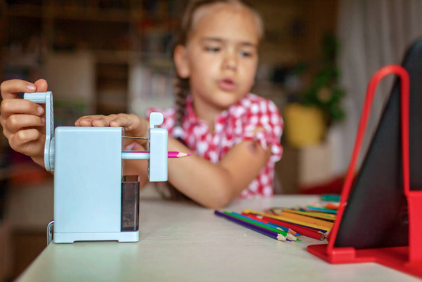 Vissza a suliba. Aranyos tudós lány élező színes ceruzák és olvasás elektronikus könyv táblagéppel egy időben, készen áll vissza az iskolába, multi-feladat és oktatási koncepció - Fotó, kép