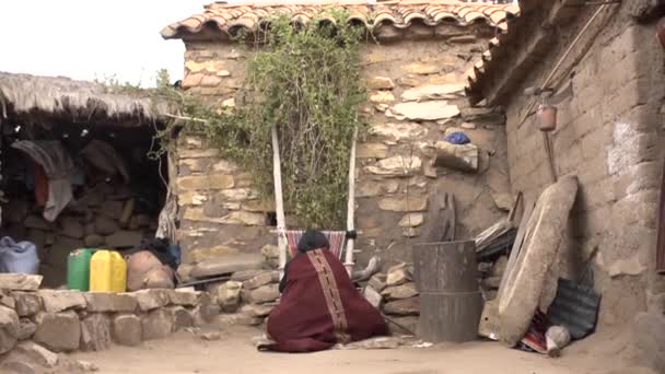 Yerel Özellikleri ve Geleneksel Giysileri Olan Kahverengi Kadın evinin önünde tahta bir çubukla dokuyor. - Video, Çekim