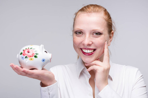 Молода щаслива жінка з скарбничкою / порцеляновим банком
  - Фото, зображення
