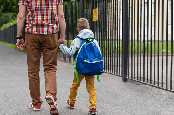 Camino a la escuela. Papá lleva a su hijo pequeño de la mano a la escuela. Regreso a la escuela
. - Foto, imagen