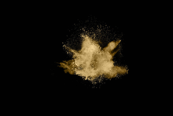 Golden powder explosion on black background. Colored cloud. Colorful dust explode. Paint Holi. - Photo, Image