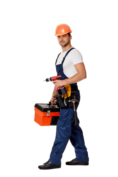 caucasian repairman worker in uniform and helmet holding cordless screwdriver. - Foto, immagini