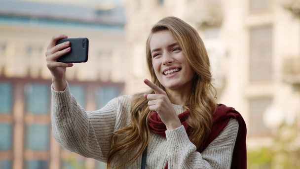 Happy girl having video call by phone outdoors. Cheerful woman using phone - Foto, Imagen