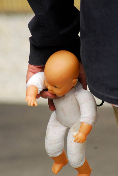 赤ちゃんの人形を片手に子供を虐待し暴力を振るう大人象徴的な絵 - 写真・画像